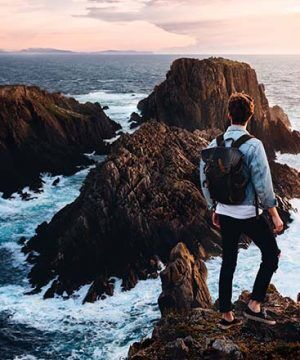 DIFC Man standing on rocks looking at the ocean