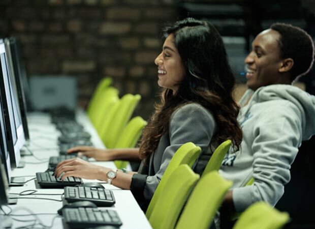 Students sitting at computers typing and laughing