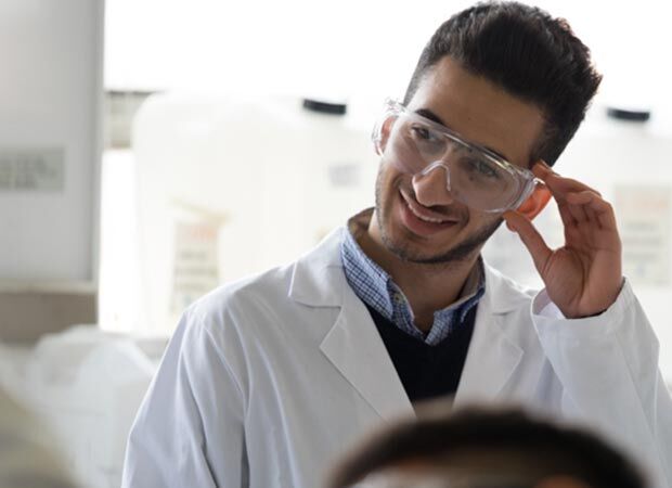 Malaysian male student wearing a lab coat and safety googles