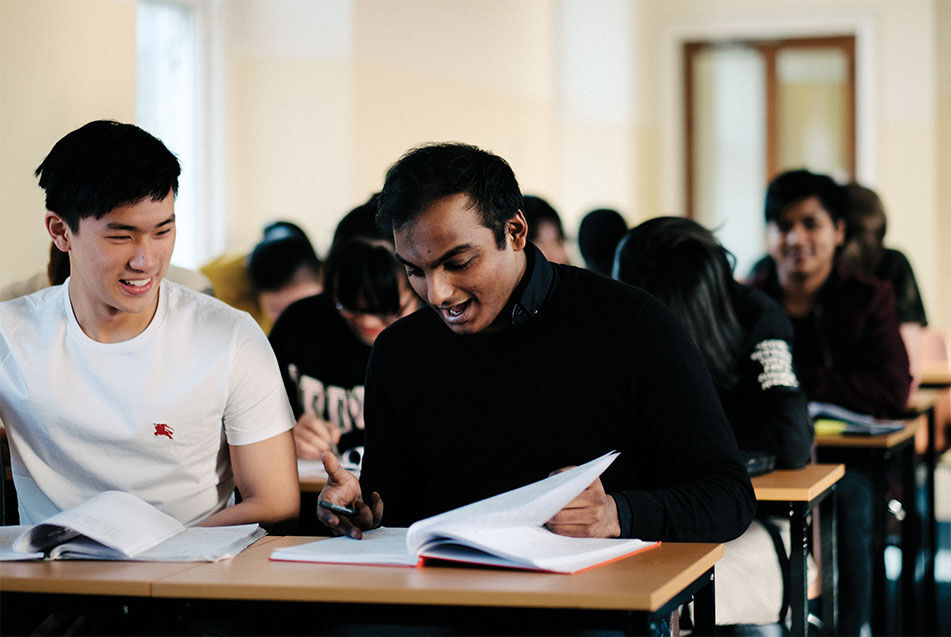 Nigerian male student sitting at a desk looking down at a notebook