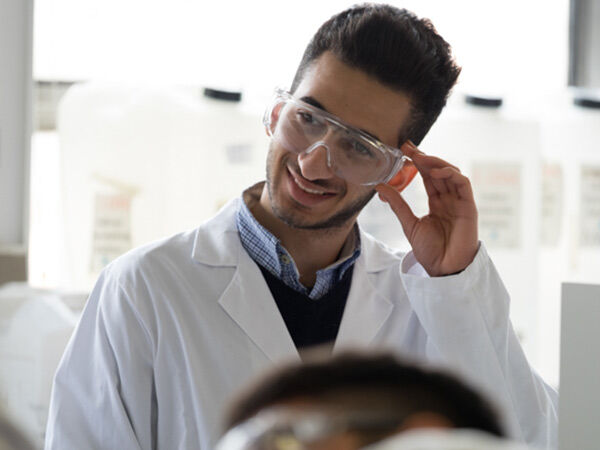 Malaysian male student wearing a lab coat and safety googles
